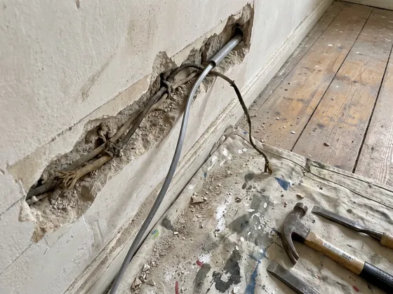 Aufgestemmter Wandschlitz mit alter Stoffleitung und neuem Kabel