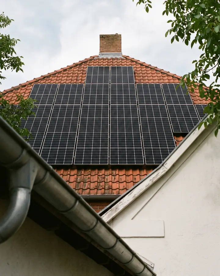 Photovoltaikmodule auf dem roten Ziegeldach eines Wohnhauses, von der Traufe aus gesehen